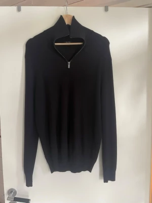 Mörkblå stickad tröja med halv dragkedja från massimo dutti - Säljer en svart stickad tröja med halv dragkedja i halsen. Tröjan har lång ärm, hög krage och ribbade muddar vid ärmslut och nederkant. Perfekt för dig som gillar en enkel och stilren look.
