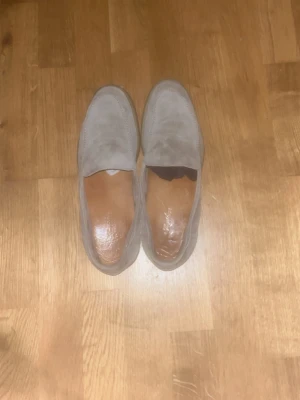 Aurelien Beige mocka loafers - Snygga loafers i beige mocka med klassisk design och rundad tå från Aurelien. Skorna har en stilren ovandel i mjukt mockamaterial och innersula i läder. Perfekta för dig som gillar en clean och enkel look.