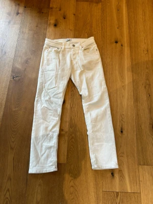Vita slim fit jeans - Säljer ett par vita jeans med rak passform och klassisk femficksdesign. Jeansen har bälteshällor, knappgylf och är tillverkade i ett mjukt bomullstyg. Lite småfläckar som lätt går bort i tvätten.