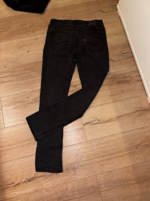 Svarta raka jeans - Säljer ett par svarta jeans med rak passform och klassiska bakfickor. Jeansen har en enkel design utan slitningar och är tillverkade i ett mjukt denimtyg. Perfekta för dig som gillar en stilren look.