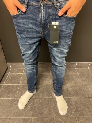 Solid Jenas  - Snygga blå jeans från Solid i modellen Rob Tapered fit. Jeansen har en smal passform med avsmalnande ben och klassisk femficksdesign. Tillverkade i stretchig denim för extra komfort. Perfekta för en trendig och avslappnad stil.