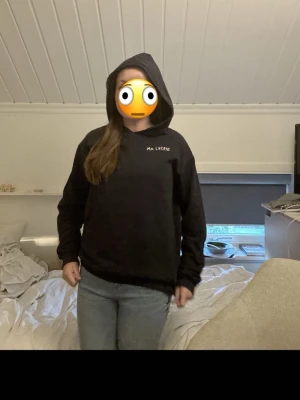 Svart hoodie med texten MA CHÉRIE - Säljer en svart hoodie med huva och vit broderad text 'MA CHÉRIE' på bröstet. Hoodien har en klassisk passform, långa ärmar och ribbade muddar. Perfekt för dig som gillar en enkel men snygg stil.