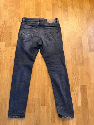 Mörkgrå jeans från Diesel - Säljer ett par klassiska mörkgrå jeans från Diesel med raka ben och två bakfickor. Jeansen har en snygg tvätt och detaljerad Diesel Industry-lapp bak i midjan. Perfekta för dig som gillar tidlös denimstil. W32 L32