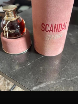 Scandal parfym från Jean Paul Gaultier - Scandal parfym från Jean Paul Gaultier i en elegant rund glasflaska med guldfärgat lock och detaljer. Kommer i en lyxig rosa sammetsförpackning med tydlig logga. Doften är känd för sin intensiva och sensuella karaktär.