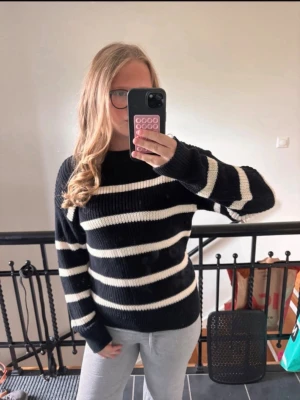 Svartvit randig stickad tröja - Snygg stickad tröja från 157 i svart med breda vita ränder. Tröjan har rund halsringning och långa ärmar med ribbstickade muddar. Perfekt för dig som gillar en klassisk och stilren look med lite edge. Storlek 150 men passar absolut XS/S