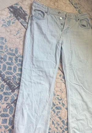 Ljusblå raka jeans med knappar H&M - Säljer ett par ljusblå jeans med raka ben, knappar och slit detaljer. 