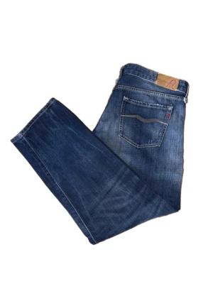 Replay jeans - Snygga blå jeans med raka ben och diskreta slitningar framtill. Klassisk femficksmodell med detaljer på bakfickan och läderpatch i midjan. Jeansen har en cool tvättad look och är tillverkade i denim, perfekt för en avslappnad stil.