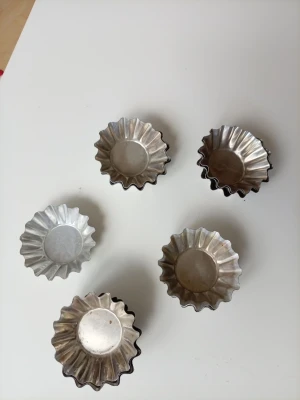 små metallformar för bakning - Säljer små bakformar i metall med räfflade kanter. Perfekta för att baka småkakor eller minipajer. Formarna är silverfärgade och har en klassisk rund form med vågig kant. Dom ha nå märken finns. 