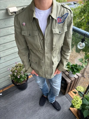 Olivgrön overshirt från Levi's - Snygg olivgrön overshirt från Levi's med feta patchdetaljer på bröstet och ärmen ✅ Bra skick endast lite missfärgad vid kragen, skriv vid funderingar och följ för mer!