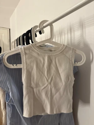 Vit croppad linnetopp från Zara - Säljer en enkel och stilren vit croppad linnetopp från Zara. Toppen är ärmlös med rund halsringning och ribbad kant. 