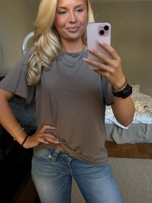 Oversized brun t-shirt med rund hals - Säljer en oversized brun t-shirt med rund hals och korta, löst sittande ärmar. T-shirten har en enkel och clean design utan tryck eller logga, perfekt för en avslappnad stil. Materialet ser mjukt och bekvämt ut, passar till jeans eller shorts.