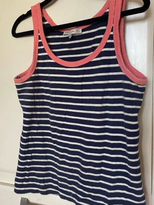 Flash linnetop Essential tvärrandig - Linnetopp Flash Essential, ärmlös med marinblå och vita ränder, rosa kantband och ett unikt bladmönster längst ner. Perfekt för dig som gillar en fräsch och somrig look. Mjuk bomullskänsla och relaxed fit.