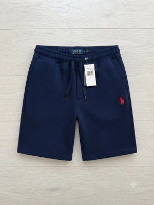 Marinblå shorts från Polo Ralph Lauren - Snygga marinblå shorts från Polo Ralph Lauren med dragsko i midjan och klassisk röd logga broderad på benet. Tillverkade i mjuk bomull, perfekta för sommardagar. Två sidofickor och bekväm passform.