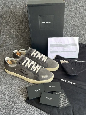 Saint Laurent skor (helt nya!) - Tja! Säljer dessa helt nya sjuka Saint Laurent skor i den mest eftertraktade CWn! Box, kvitto, extrasnören, kuvert med kort och 2st stora dustbags medföljer! Storlek 45 med Innermåttet på 29,5cm. Modellen är SL/06 court grey canvas/suede. Skorna är garanterat äkta vilket jag står för (kolla omdömen). Hör av dig vid intresse av köp! Mvh DC ♦️