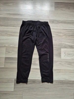 Svarta träningsleggings från Röhnisch - Säljer ett par svarta tränningsleggings från Röhnisch med elastisk midja och diskret logga på benet. De är i stretchigt material och har en enkel, klassisk design som passar perfekt till träning eller chill.
