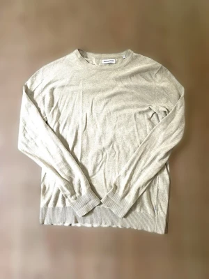  Jack & Jones tröja  - Snygg beige tröja från Jack & Jones i mjukt och tunt material. Tröjan har rund halsringning, långa ärmar och ribbade muddar vid ärmslut och nederkant. Perfekt för en clean och stilren look samt hösten 