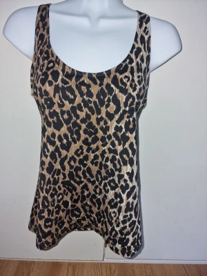Leopardmönstrad linnetopp från Dolce & Gabbana  - Snygg leopardmönstrad linnetopp i beige och svart. Kan stylas både löst eller knytas framtill för en cool look.