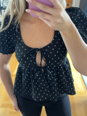 Prickig blus med knytdetaljer - Söt svart blus med vita prickar och knytdetaljer framtill. Använd enstaka gång :)