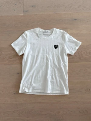  Comme des Garçons Play T-shirt - Säljer en clean vit T-shirt från Comme des Garçons Play | skicket på tröjan är väldigt bra, bara att den har en fläck som man kan se på bild 3 | säljer den för att den är för liten för mig | tags medföljer | pris kan diskuteras vid en snabb affär!