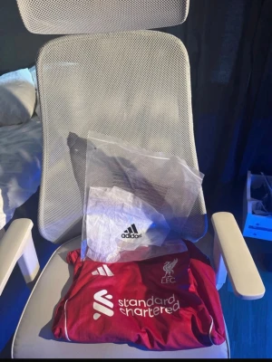 Liverpool röd matchtröja ISAK 9 - Säljer en röd Liverpool matchtröja med ISAK och nummer 9 på ryggen. Tröjan har vita detaljer, klubbmärke och sponsorloggor på bröstet samt vita ränder på axlarna. Qr cod kan scannas för att komma direkt till adidas hemsida och påse skickas självklart med skriv om ni undrar något!!