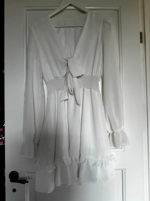 Vit klänning  - Vit klänning från Dressy. Använd en gång, hänger några trådar vid vänster ärm (se bild 6) utöver det finns det inga defekter och det är lätt att åtgärda. Passar perfekt till studenten!