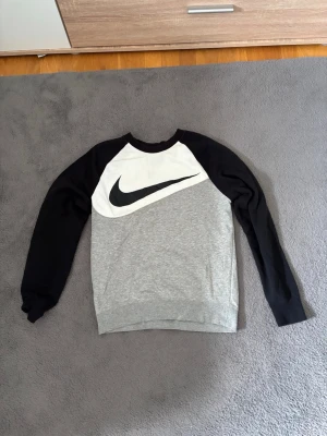 Nike sweatshirt med svartvita ärmar - Snygg sweatshirt från Nike med svartvita raglanärmar och grå kropp. Vid funderingar eller frågor är det bara att höra av sig!