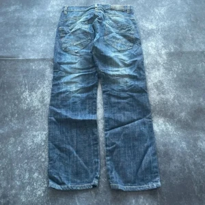 Sam's Jeans 2000-tals whiskered jeans för herrar i storlek W31 L31 - Mycket fint skick och snygg tvätt!  Mått: Midja: 41 cm Benslut: 20 cm Lår: 32 cm Totallängd: 102 cm W/L är uppskattade utifrån måtten.  Skickas inom ett dygn Spara på priset och frakten genom att sätta ihop ett paket  Mer information finns på min profil 16-309