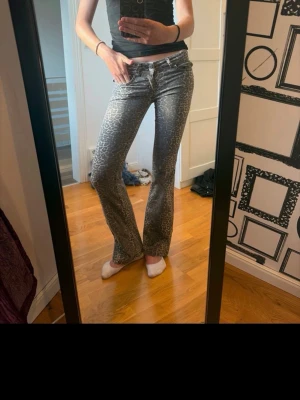 Leopardmönstrade bootcut jeans - Snygga grå jeans med leopardmönster och bootcut-modell. Jeansen har klassisk femficksdesign och låg midja. Perfekta för dig som vill sticka ut med ett coolt mönster och trendig passform.
