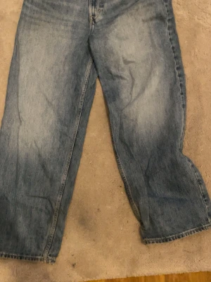 Baggy jeans från H&M ljusblå - Baggy jeans från H&M i ljusblå denim med bred passform och klassisk femficksdesign. Jeansen har en avslappnad look och är tillverkade i bomull. 