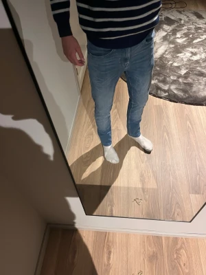 Ljusblå slim fit jeans herr - Säljer ett par ljusblå slim fit jeans med klassisk femficksdesign och normal midja. Jeansen har en modern, smal passform och är tillverkade i denim med lätt stretch för extra komfort. Perfekta för dig som gillar en stilren och enkel look. Storlek 27/30 