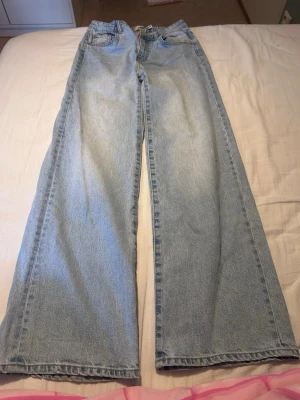 Ljusblå raka jeans från 157 - Säljer ett par ljusblå jeans från 157 med rak passform och klassisk femficksdesign. Jeansen har låg midja och breda ben, perfekta för en avslappnad och trendig look. Tillverkade i mjuk bomull för skön känsla hela dagen.
