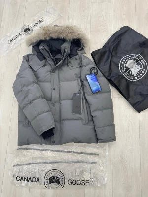 Canada Goose jacka  - Hej, jag säljer nu det som finns i lager innan vi fyller på mer, Canada goose black label wyndham i färgen grå är nu inne och vill hitta en ägare som kan ta hand om den, NFC tag funkar, äkta päls med stämpel som står vid lappen. Storlek XL/L