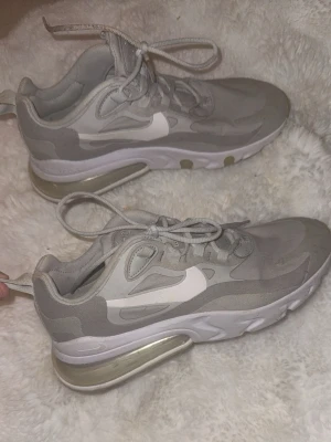  Nike skor gråa - Säljer ett par gråvita Nike Air Max sneakers med camomönster och vit sula. Skorna har synlig luftdämpning i hälen och klassisk Nike-logga på sidan. Snygga detaljer och sköna att ha på sig, perfekta för dig som gillar streetwear.