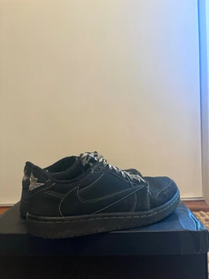 Air Jordan 1 Low Travis Scott Black edition  - Ett par svarta Air Jordan 1 low Travis scotts som kommer med 3 olika sorters skosnören och en svart Nike låda. Som ni ser i bilderna så är skorna använda och kan därför ta emot bud också! Men placera gärna seriösa bud.
