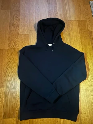 Marinblå Pier one hoodie. Storlek S - En stilren marinblå Pier One hoodie med huva och dragsnören. Klassisk modell utan synligt tryck eller logga, perfekt för en clean look. Tillverkad i mjukt material ochu har ribbade muddar vid ärmar och nederkant. Passar till det mesta och är superbekväm.