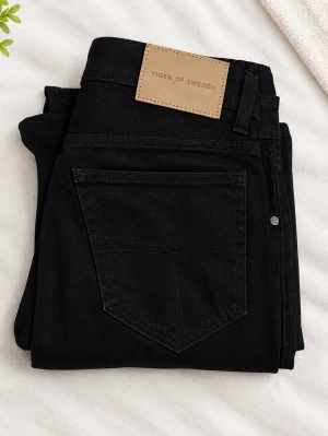 Svarta raka jeans Tiger of Sweden - Snygga svarta jeans från Tiger of Sweden med rak passform och klassisk femficksdesign. Jeansen har en stilren look med svart denim och en beige patch med logga bak i midjan. Perfekta till en trendig och avslappnad stil.