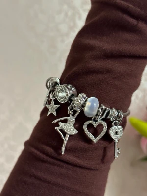 Silverfärgat armband med berlocker - Snyggt armband i rostfritt silverfärg med flera berlocker. 