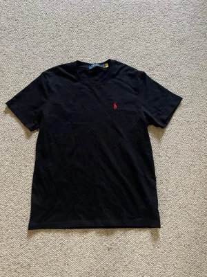 Polo Ralph lauren tshirt  - En svart Polo Ralph lauren tshirt med röd logga. Den är i storlek S och i nytt skick. Pris kan diskuteras och skriv om du har några frågor. 