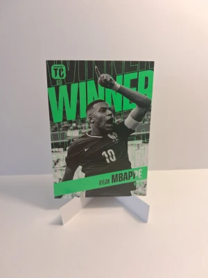 Fotbollssamlarkort Kylian Mbappé - Samlarkort med Kylian Mbappé från Panini Top Class. Kortet har svartvit design med gröna detaljer och texten WINNER. Baksidan visar statistik och en bild på Mbappé i Frankrikes landslagströja. Perfekt för dig som gillar fotboll och samlar på sportkort.