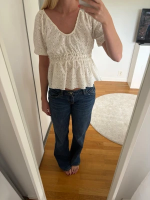 Vit broderad topp med puffärm - Superfin vit topp från ONLY med broderat hålmönster, puffärmar och smockad midja.  Tunt och luftigt material.  Djup rundad ringning både fram och bak. Toppen är i storlek xxs men passar absolut en s också eftersom den är större i storleken men även stretchig. 