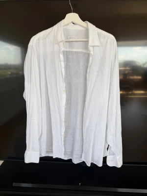 Vit linneskjorta från Massimo Dutti - Klassisk vit skjorta i 100% linne från Massimo Dutti. Skjortan har lång ärm, knappar framtill och en avslappnad passform. Perfekt för varma dagar och enkel att styla till olika outfits.