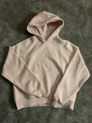 Ljusrosa hoodie med huva - En stilren ljusrosa hoodie med huva och magficka. Har en liten fläck på magfickan (syns på bild 2). Ändast använts fåtal gånger. Storlek xs men passar även s💕