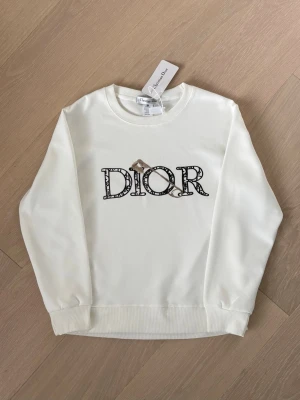 Vit Hoodie - Vit D1or-hoodie. Helt ny med prislapp. Storlek XS/S Be om fler bilder. Skickas inom 24 timmar📦