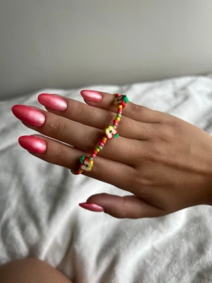 Färgglatt pärlarmband med äpplen  - Ett handgjort armband med små färgglada pärlor och äpplen i gult, rött och grönt. Armbandet har en tunn silverfärgad kedja och passar perfekt för dig som gillar lekfulla accessoarer. Söt detalj till din outfit!💕