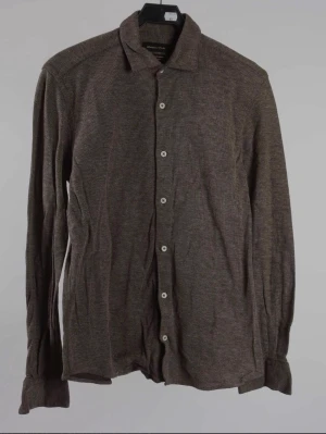 Massimo Dutti Skjorta - Snygg brun skjorta med diskret mönster och klassisk krage. Skjortan har långa ärmar och vita knappar framtill samt vid ärmsluten. Perfekt för en stilren och avslappnad look.