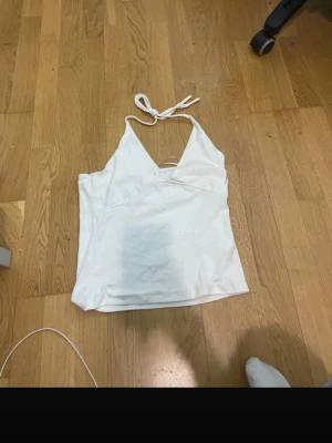 Vit halterneck linnetopp - Säljer en vit halterneck linnetopp i storlek M från 157. Toppen har knyt i nacken och en djup v-ringning framtill. Perfekt för varma dagar och enkel att styla med olika outfits.