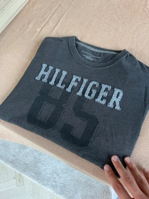 Mörkgrå Hilfiger t-shirt med tryck - Riktigt fet Tommy hilfiger T-shirt med påsytt tryck🙌Storlek S. Hör av dig vid frågor 
