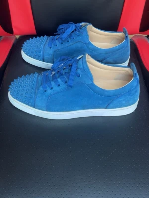 Blåa Christian Louboutin skor - Säljer ett par blåa Christian Louboutin sneakers i väldigt fint skick, storlek 43.5.
