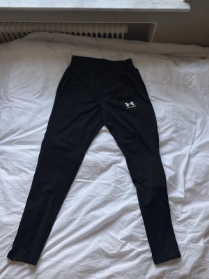 Svarta träningsbyxor från Under Armour - Säljer ett par Under Armour träningsbyxor i bra skick. Använda få gånger och väl omhändertagna. Inga fläckar, hål eller skador. Snygga och bekväma byxor som passar perfekt till träning eller vardag.