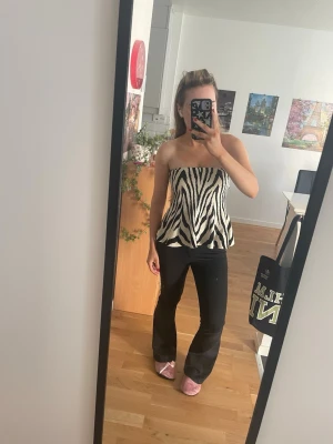 Skit snygg trendig zebramönstrad topp🖤 - Säljer en snygg axelbandslös topp med zebramönster i svart och vitt. Toppen har en bandeauformad överdel och en lätt utsvängd nederdel som ger en cool siluett. Perfekt för dig som vill sticka ut med ett djurmönster.